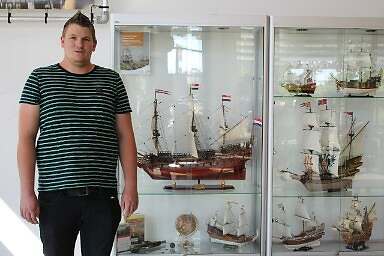 Danny showt op deze foto zijn verzameling zelf gemaakte schepen. Hij blikt trots de camera in, in de vitrinekast naast hem staat zijn kostbare collectie.